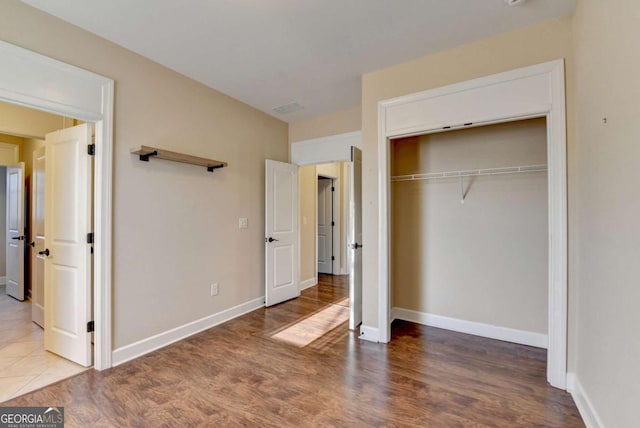 unfurnished bedroom featuring wood finished floors, a closet, and baseboards
