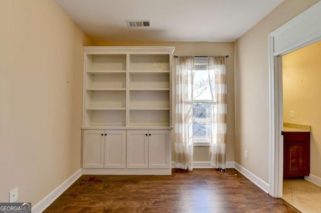interior space featuring baseboards, dark wood-type flooring, and visible vents