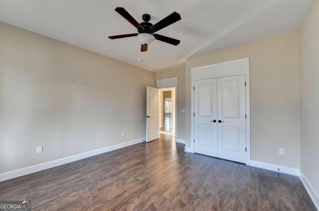 unfurnished bedroom with vaulted ceiling, a ceiling fan, a closet, baseboards, and dark wood-style flooring