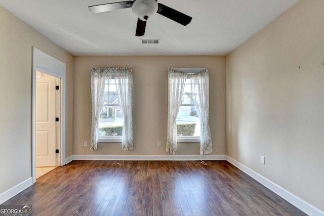 spare room featuring wood finished floors, visible vents, baseboards, and ceiling fan