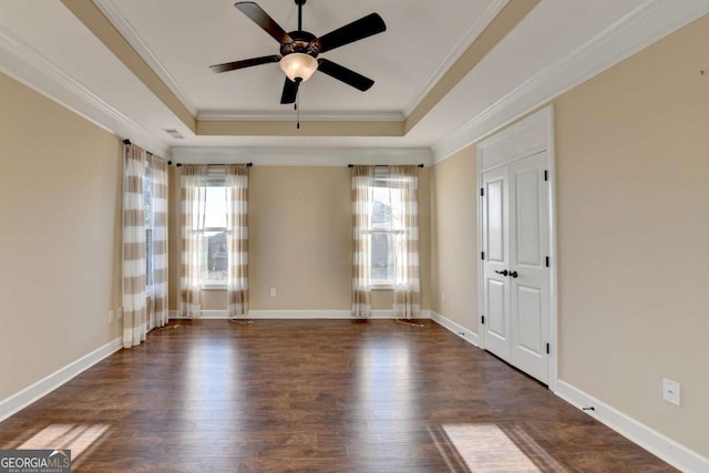 spare room featuring a ceiling fan, a tray ceiling, dark wood finished floors, ornamental molding, and visible vents