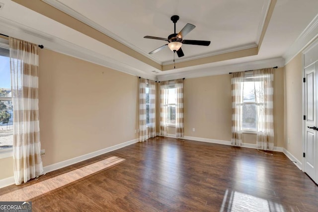 unfurnished room with wood finished floors, a tray ceiling, a wealth of natural light, and ornamental molding