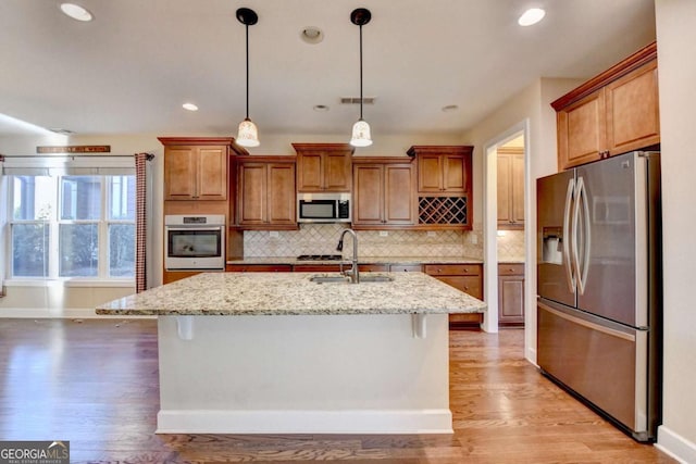 kitchen with light wood-type flooring, stainless steel appliances, baseboards, and a sink
