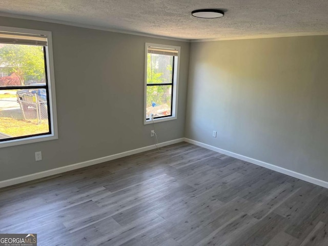 spare room featuring wood finished floors, a textured ceiling, and baseboards