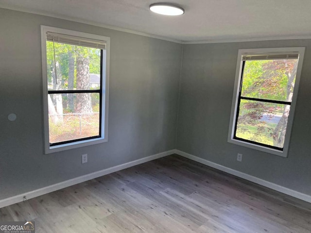 spare room featuring baseboards, wood finished floors, and crown molding