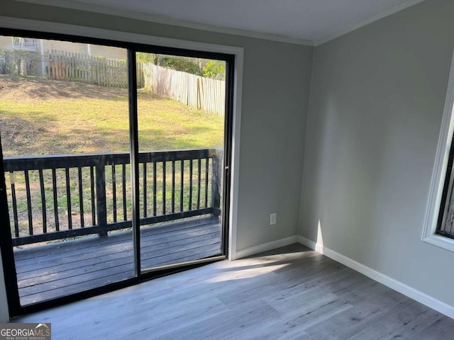 doorway to outside with wood finished floors, baseboards, and ornamental molding