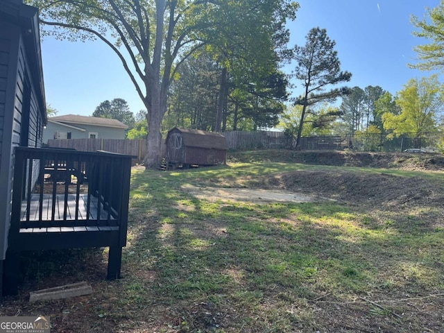 view of yard with a wooden deck, a fenced backyard, a storage shed, and an outdoor structure