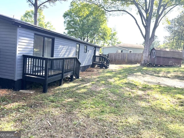 view of yard with fence, a deck, an outdoor structure, and a shed