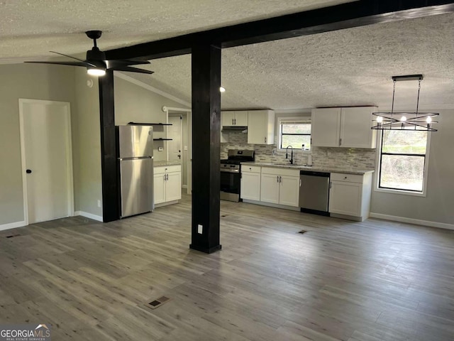 kitchen featuring white cabinets, a sink, baseboards, decorative backsplash, and appliances with stainless steel finishes