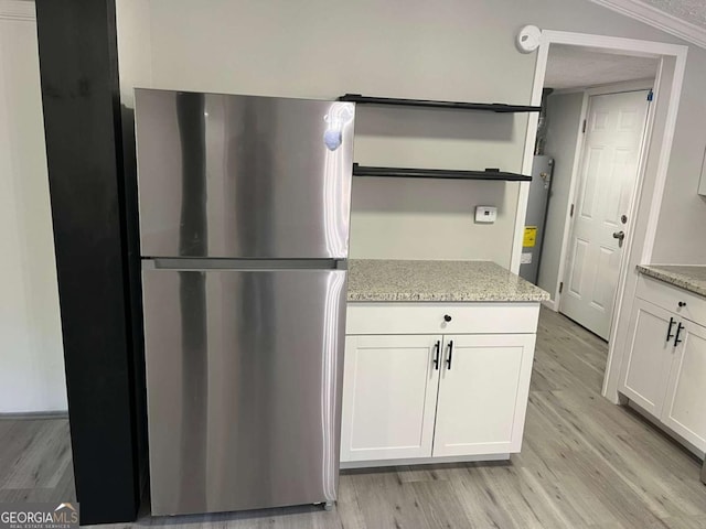 kitchen featuring open shelves, freestanding refrigerator, light wood finished floors, and white cabinetry