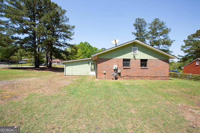 back of house with brick siding, a yard, and fence