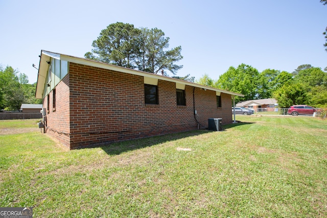 view of property exterior featuring brick siding, a yard, and fence