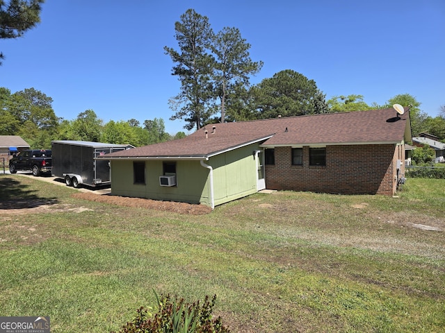 exterior space with roof with shingles, brick siding, a yard, and cooling unit