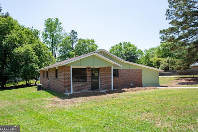 view of front of property with brick siding, cooling unit, a front yard, and fence
