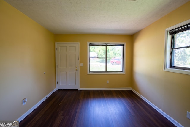 spare room with dark wood finished floors, baseboards, a wealth of natural light, and a textured ceiling