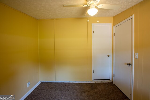 carpeted spare room featuring ceiling fan, a decorative wall, and a textured ceiling