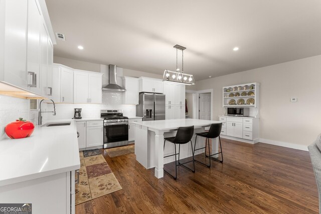 527 Abby, Clayton, GA 30525 - kitchen featuring stainless steel appliances, wall chimney exhaust hood, a breakfast bar, dark wood-style floors, and a center island