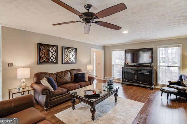 living room featuring a textured ceiling, wood finished floors, a brick fireplace, and a ceiling fan