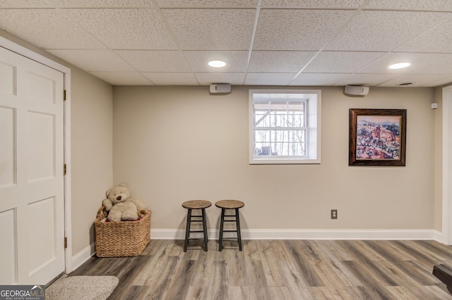 interior space featuring baseboards, a wood stove, wood finished floors, and a paneled ceiling