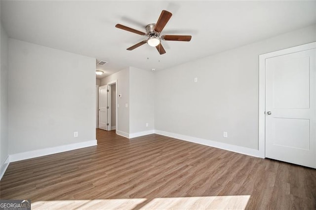 empty room with baseboards, wood finished floors, visible vents, and ceiling fan