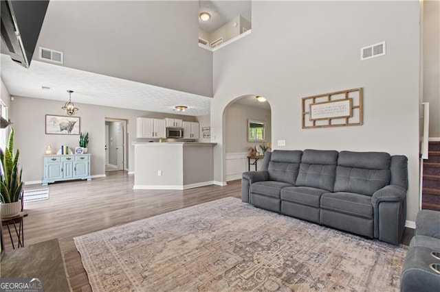 living room featuring visible vents, wood finished floors, and a towering ceiling