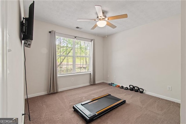 exercise area with carpet, a textured ceiling, visible vents, baseboards, and ceiling fan