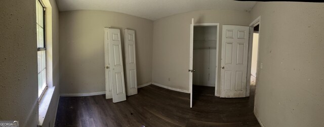 unfurnished bedroom featuring baseboards, wood finished floors, and a closet