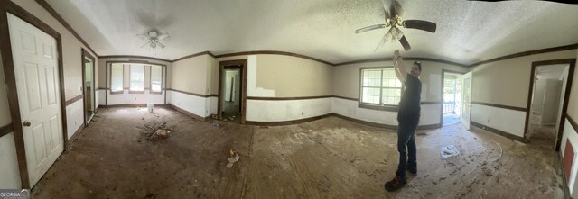 unfurnished room with a ceiling fan, baseboards, a wealth of natural light, and crown molding