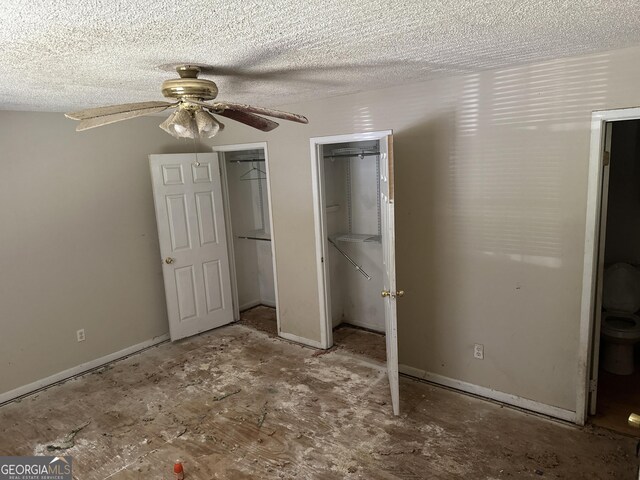 unfurnished bedroom featuring ceiling fan, baseboards, a textured ceiling, and two closets