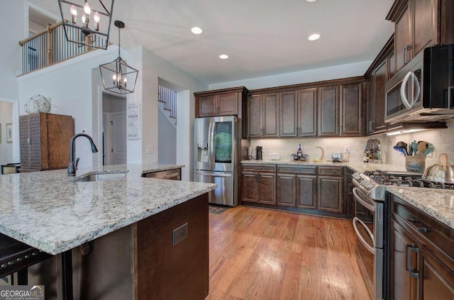 17 Ivy Stone Ct SE, Cartersville, GA 30120 - kitchen featuring dark brown cabinets, decorative backsplash, an inviting chandelier, light wood-style flooring, and appliances with stainless steel finishes