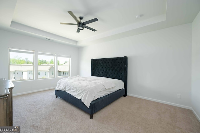bedroom with a raised ceiling, carpet floors, baseboards, and ceiling fan
