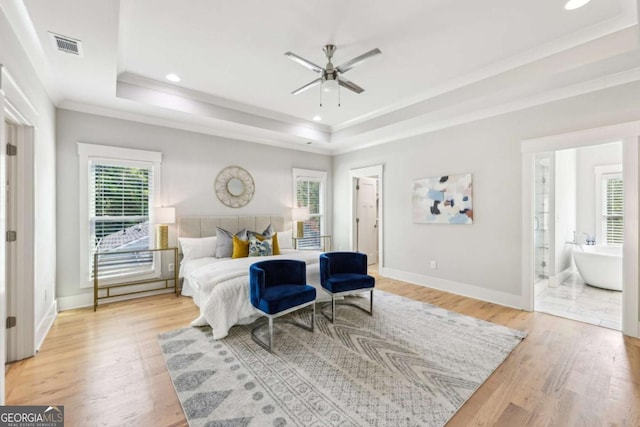 bedroom with a raised ceiling, light wood-type flooring, and ornamental molding