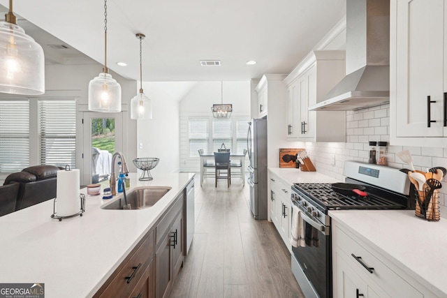 kitchen featuring a sink, light countertops, wall chimney exhaust hood, appliances with stainless steel finishes, and recessed lighting