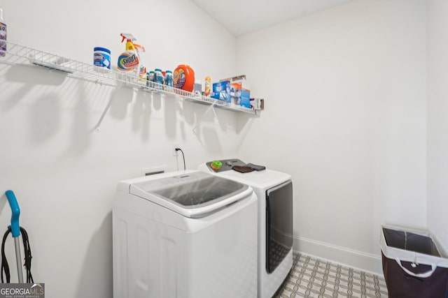 clothes washing area featuring light floors, washing machine and clothes dryer, baseboards, and laundry area