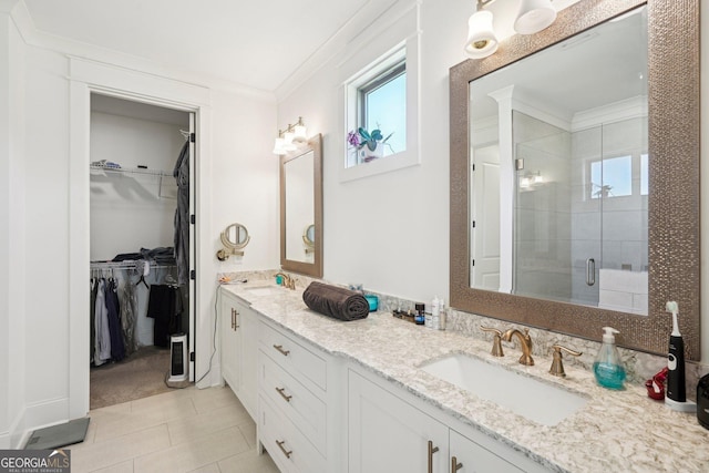bathroom with a spacious closet, a sink, a shower stall, and crown molding