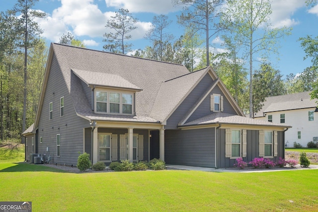 craftsman-style house featuring central air condition unit, board and batten siding, a shingled roof, and a front yard