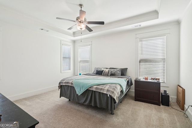 bedroom featuring visible vents, light carpet, baseboards, and a tray ceiling