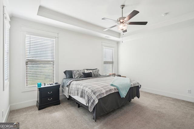 bedroom featuring light carpet, a ceiling fan, baseboards, and a raised ceiling