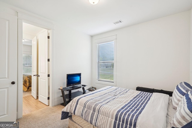 bedroom with visible vents and light carpet