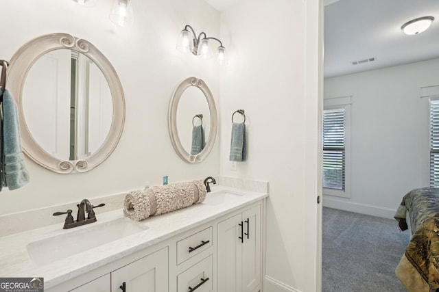 full bath featuring double vanity, visible vents, baseboards, and a sink