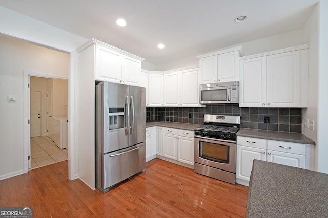 15 Boxelder Ct, Dallas, GA 30132 - kitchen featuring white cabinets, stainless steel appliances, dark countertops, decorative backsplash, and wood finished floors