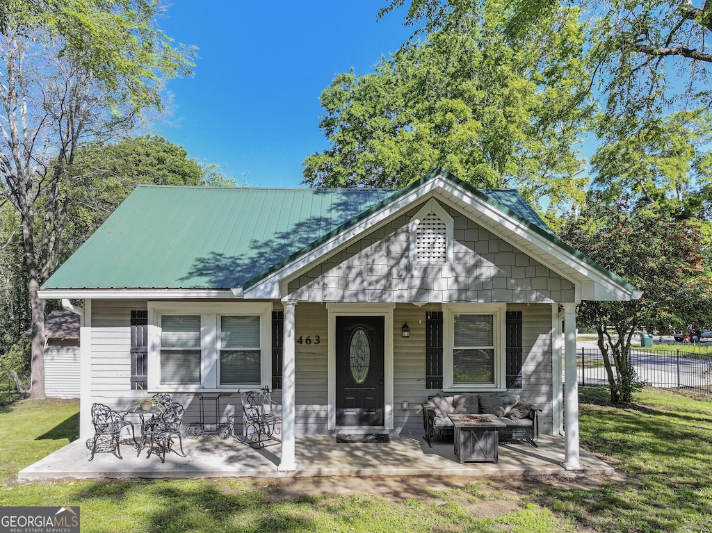 463 State St, Commerce, GA 30529 - bungalow featuring a front lawn, a fire pit, fence, a porch, and metal roof