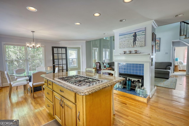 4157 Town Branch Ct SW, Covington, GA 30014 - kitchen with stainless steel gas cooktop, ornamental molding, a tiled fireplace, and a center island