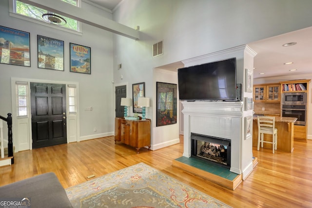 4157 Town Branch Ct SW, Covington, GA 30014 - entrance foyer with light wood-style floors, a high ceiling, a fireplace, and visible vents