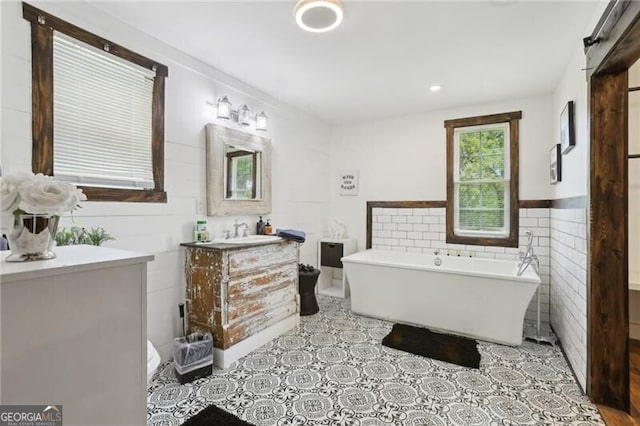 1060 Stephen St, Greensboro, GA 30642 - bathroom featuring vanity, a freestanding tub, tile walls, and wainscoting