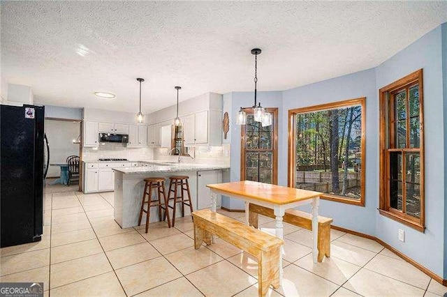 dining area featuring baseboards, a textured ceiling, and light tile patterned floors