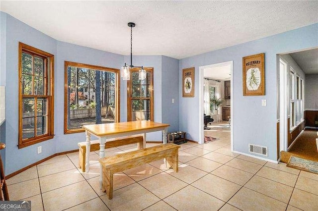 dining space with light tile patterned floors, baseboards, a textured ceiling, and visible vents