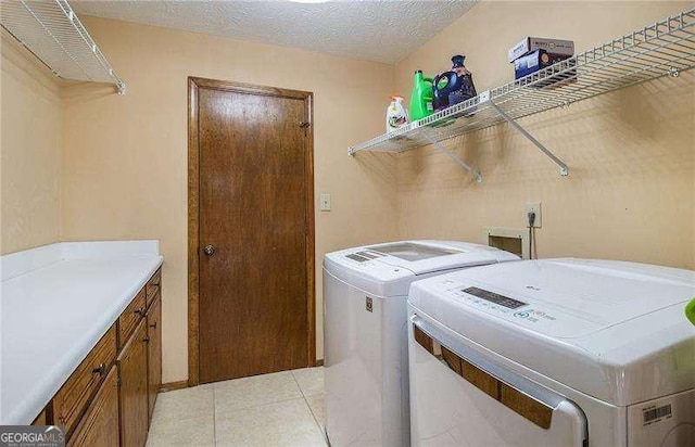 clothes washing area with cabinet space, light tile patterned floors, and washer and dryer