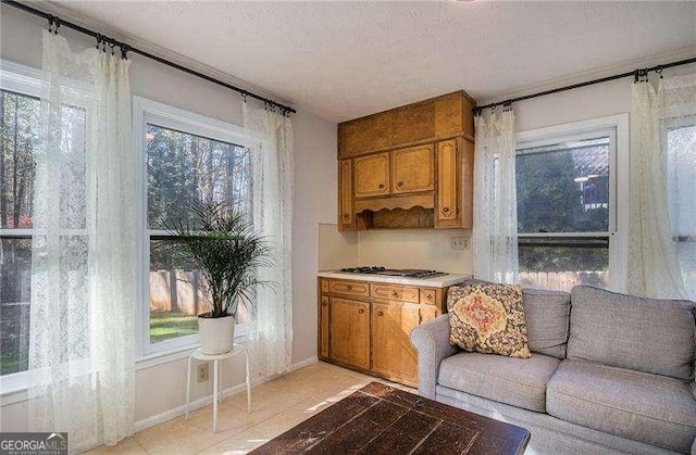 interior space featuring gas cooktop, light tile patterned floors, and baseboards