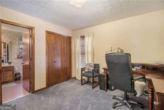 carpeted office featuring a textured ceiling